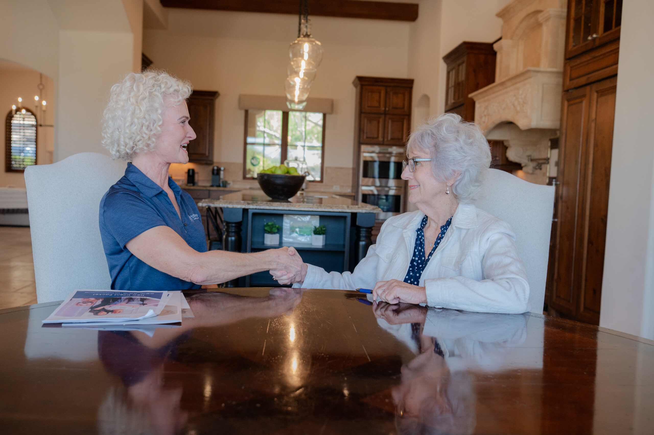 A care manager from Total Care Connections and a senior client smiling and shaking hands, agreeing on a care plan.