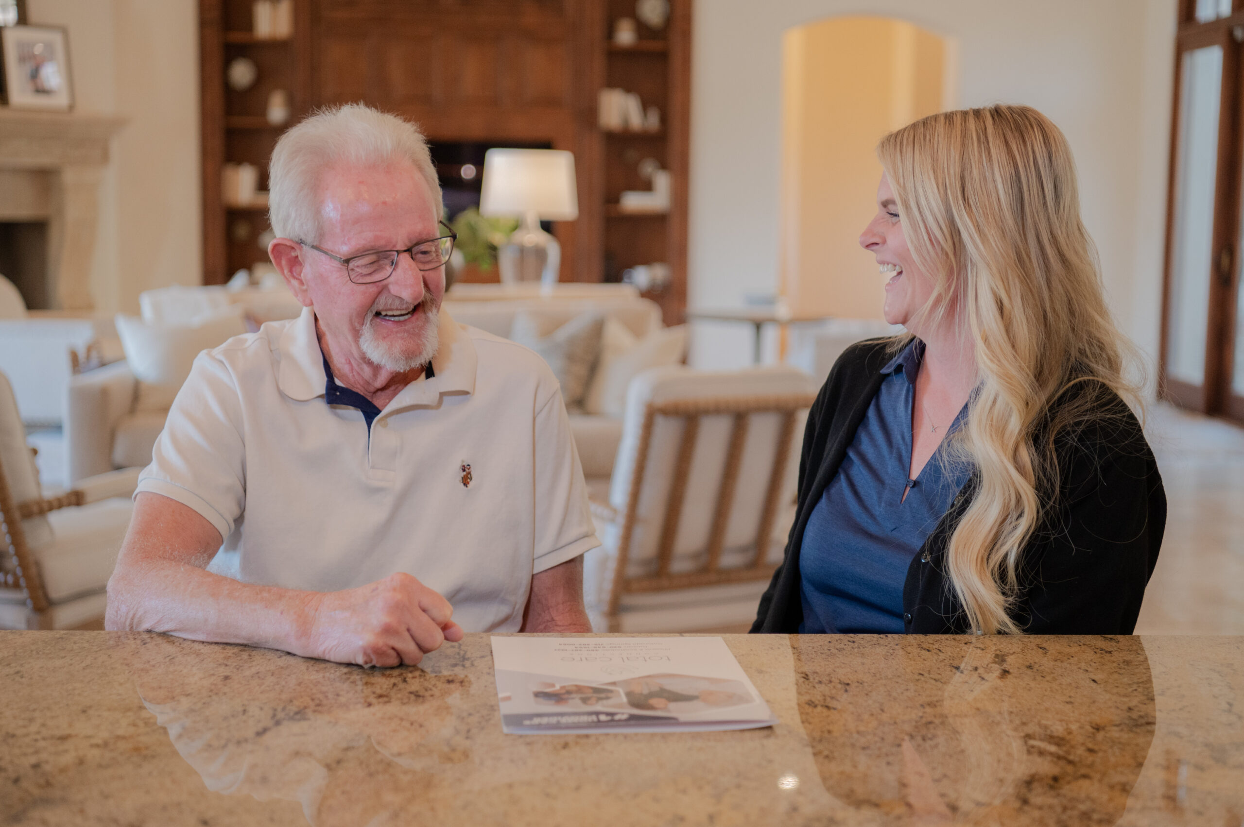 A male senior and a caregiver from Total Care Connections engaged in a happy conversation.