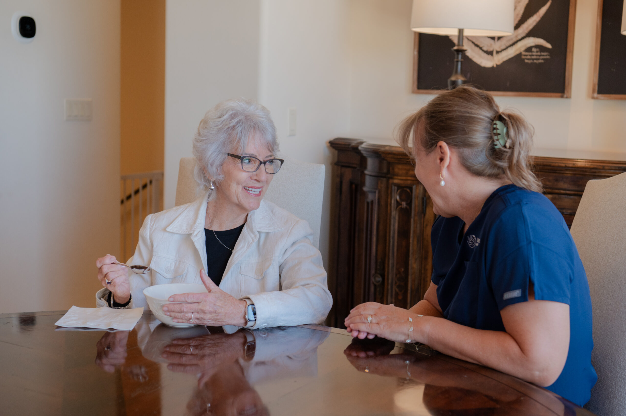 A female caregiver from Total Care Connections accompanying a senior client while eating.