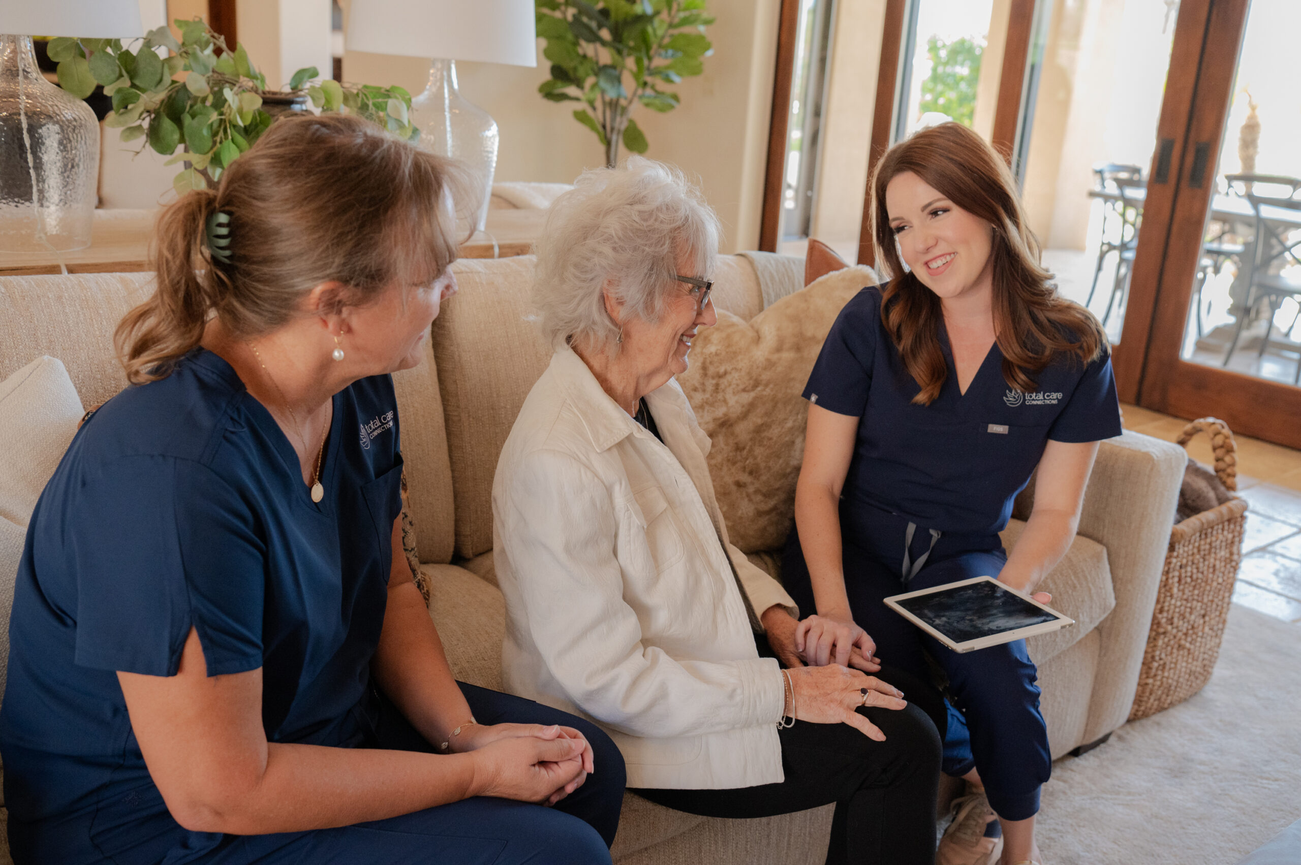 A care manager and a caregiver from Total Care Connections talking to a senior client.